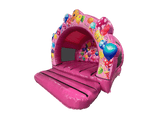 Airquee pink inflatable party bouncer with a contoured arch, balloon artwork, and netted sides for events.