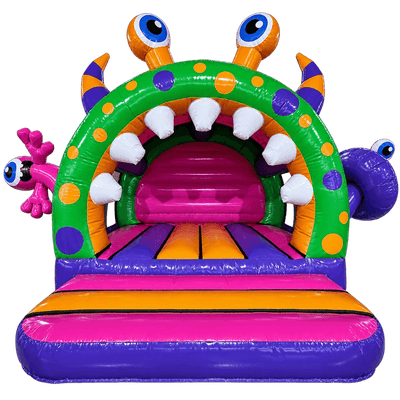 A colorful inflatable monster-themed bounce house with a green arch, purple mouth interior, white teeth, orange and purple spots, eye details on the horns, a pink side mouth, and a purple striped entryway.
